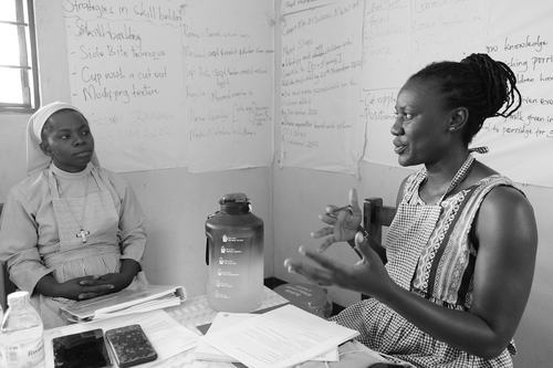 A black and white photo of SPOON Nutrition Technical Officer Lutgard talking with a nun