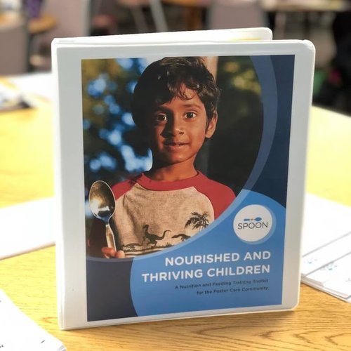 A photo of a binder containing SPOON's Nourished and Thriving Toolkit